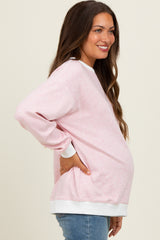 woman wearing a pink striped maternity sweatshirt with long sleeves and a visible baby bump