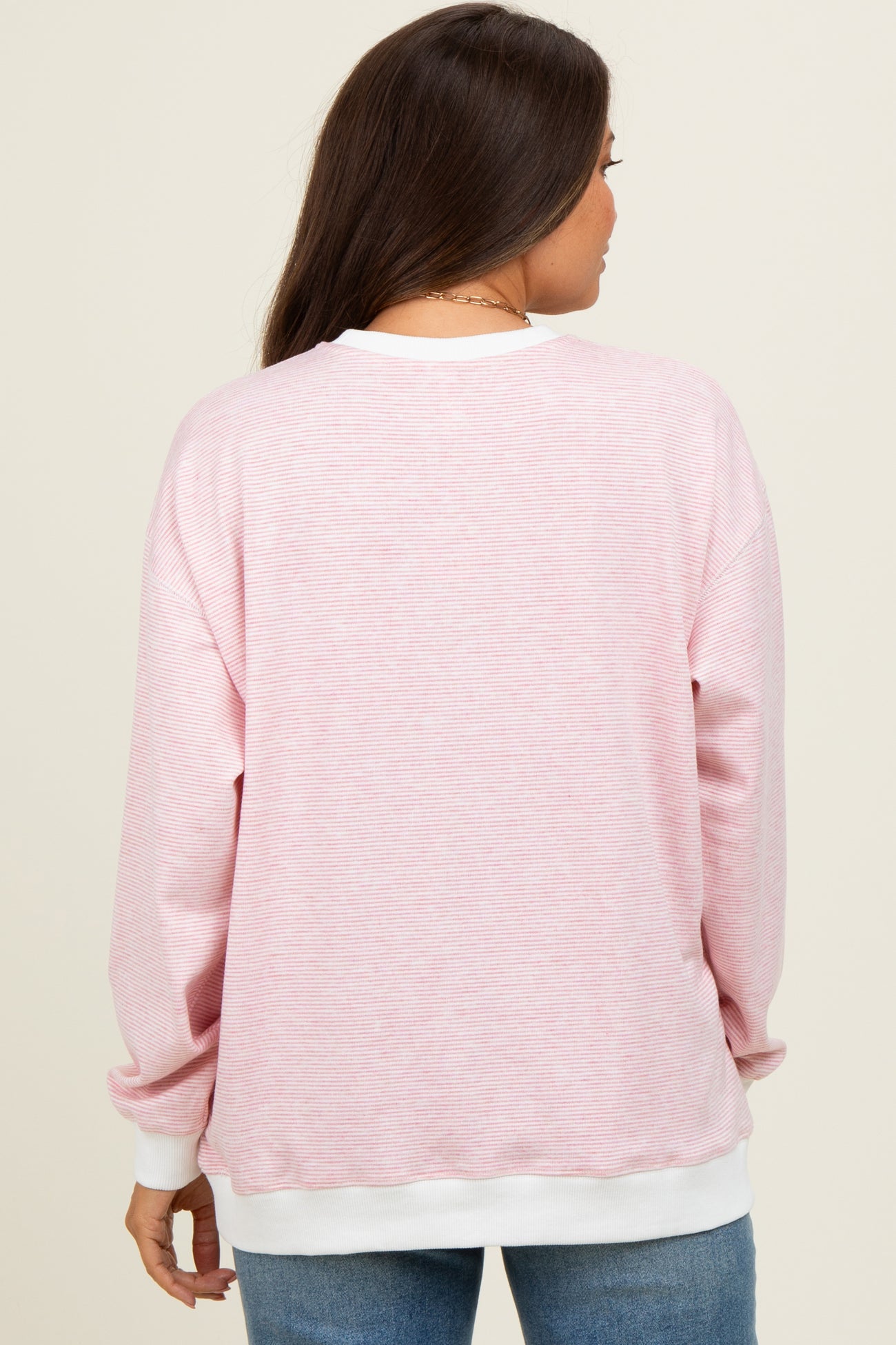 woman wearing a pink striped maternity sweatshirt with white cuffs, showing the back view