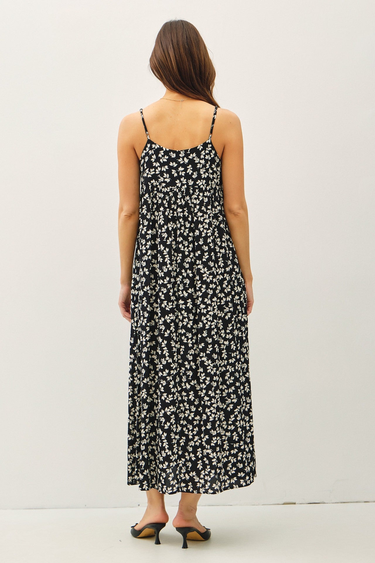 woman wearing a black floral maxi dress with spaghetti straps, seen from the back