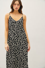 woman wearing a black maxi dress with a white floral pattern and adjustable spaghetti straps