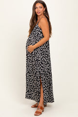 woman wearing a black and white floral maternity maxi dress with a side slit and holding her baby bump
