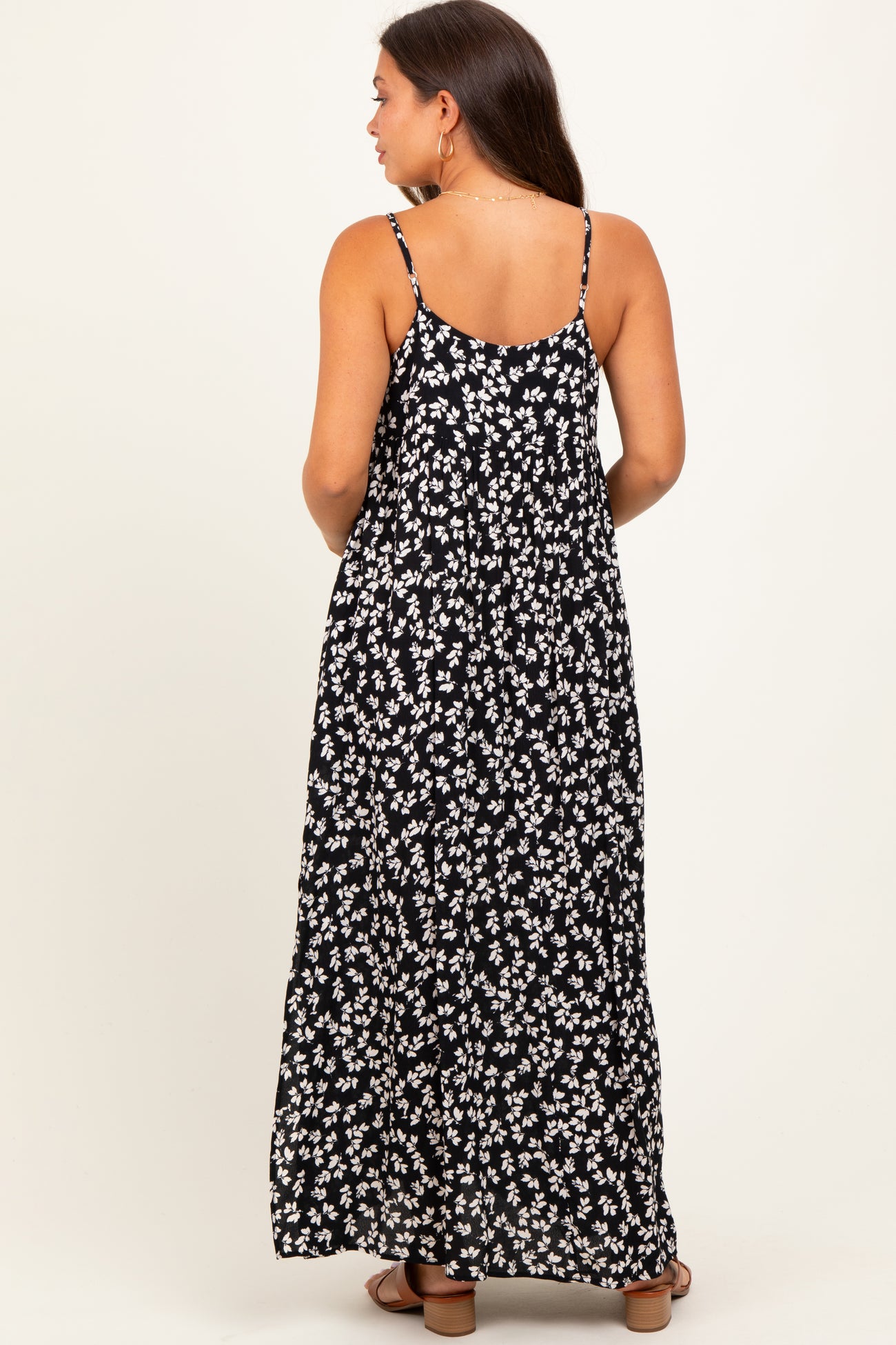 woman wearing a black floral maternity maxi dress with spaghetti straps, showing a baby bump from the back