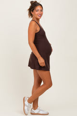 woman wearing a dark brown sleeveless maternity dress with a flared skirt and a visible baby bump