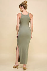 woman wearing a long olive green ribbed maxi dress with a thigh-high slit and a racerback style