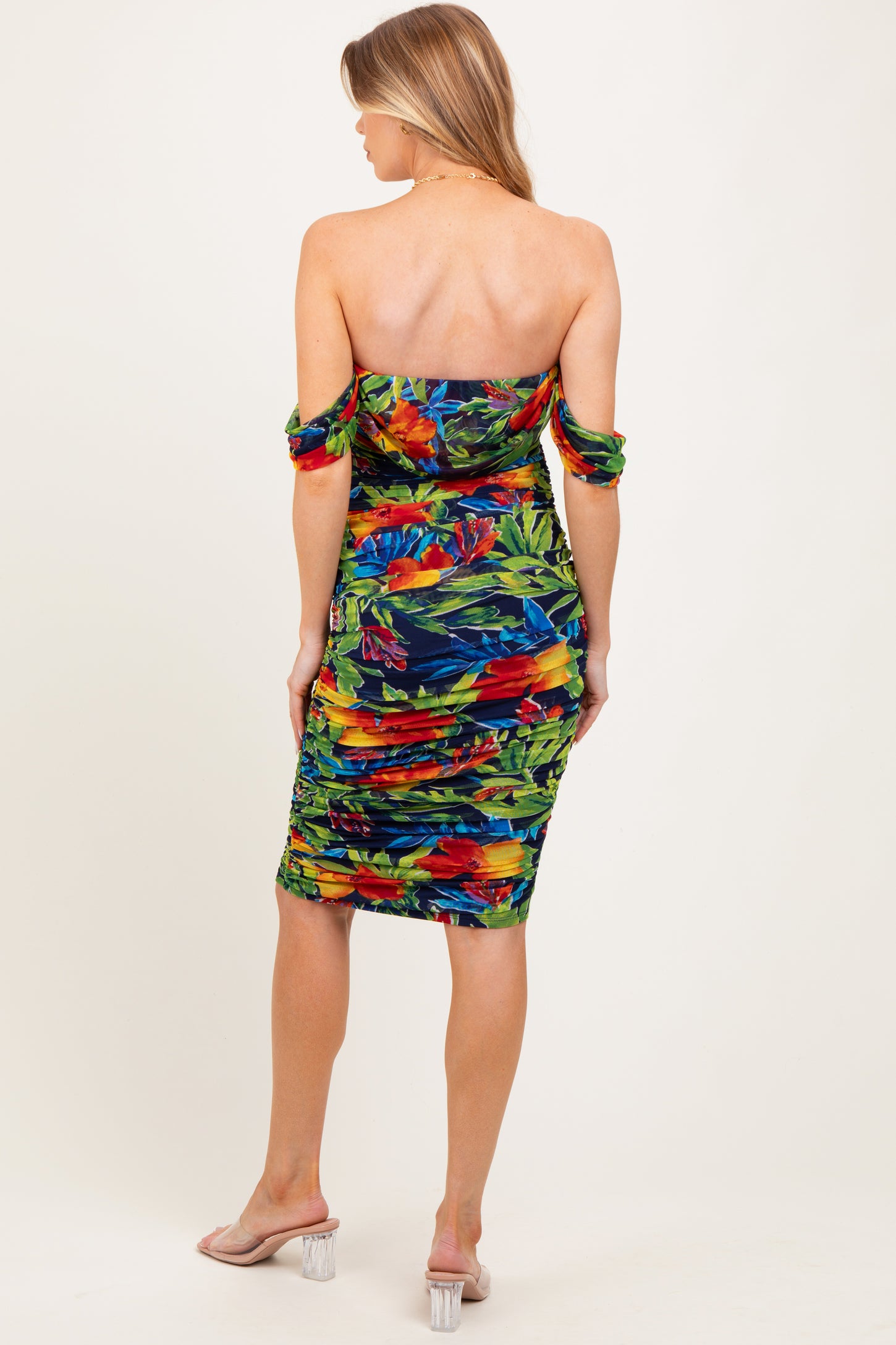 woman wearing a tropical print off-the-shoulder maternity dress with ruching and a fitted silhouette