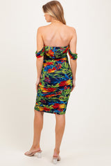 woman wearing a tropical print off-the-shoulder maternity dress with ruching and a fitted silhouette