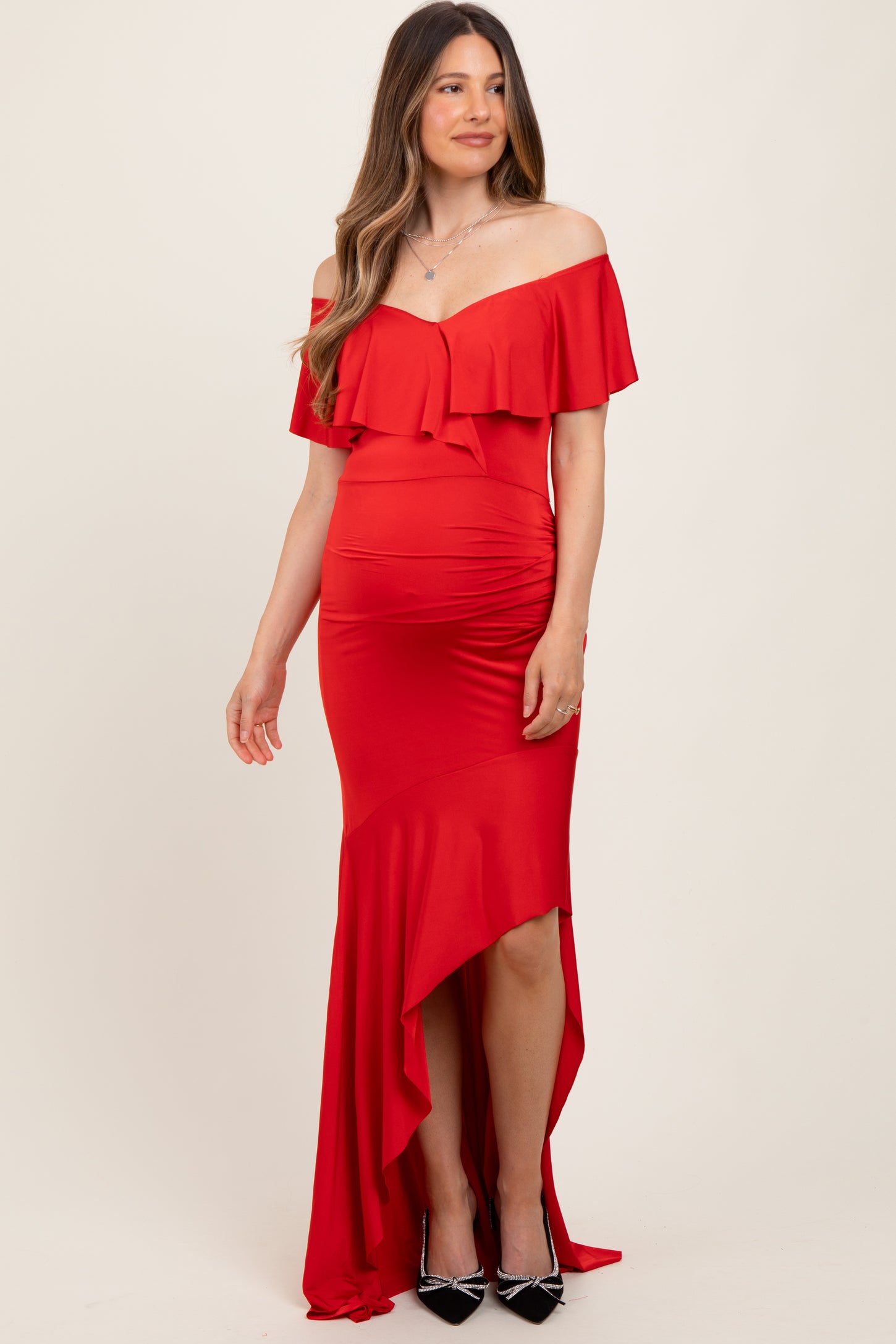 woman wearing a red off-the-shoulder maternity dress with ruffle detail and high-low hemline
