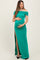 woman wearing a green off-the-shoulder maternity gown with side ruching and a thigh-high slit, holding her baby bump