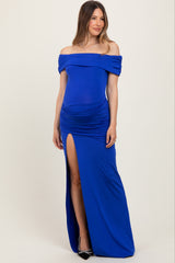woman wearing a royal blue off-the-shoulder maternity dress with side ruching and a high slit, showcasing her baby bump