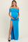 woman wearing a bright blue off-the-shoulder maternity gown with a thigh-high slit and crisscross detailing, showcasing her baby bump