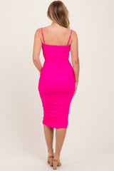 woman wearing a bright pink bodycon midi dress with ruched detailing and thin straps, viewed from the back