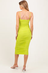 woman wearing a fitted neon green maternity midi dress with ruched detailing and spaghetti straps