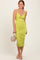 woman wearing a fitted lime green midi dress with ruching details and spaghetti straps, holding a small handbag