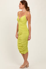 woman wearing a lime green midi dress with ruching, adjustable spaghetti straps, and a plunging neckline
