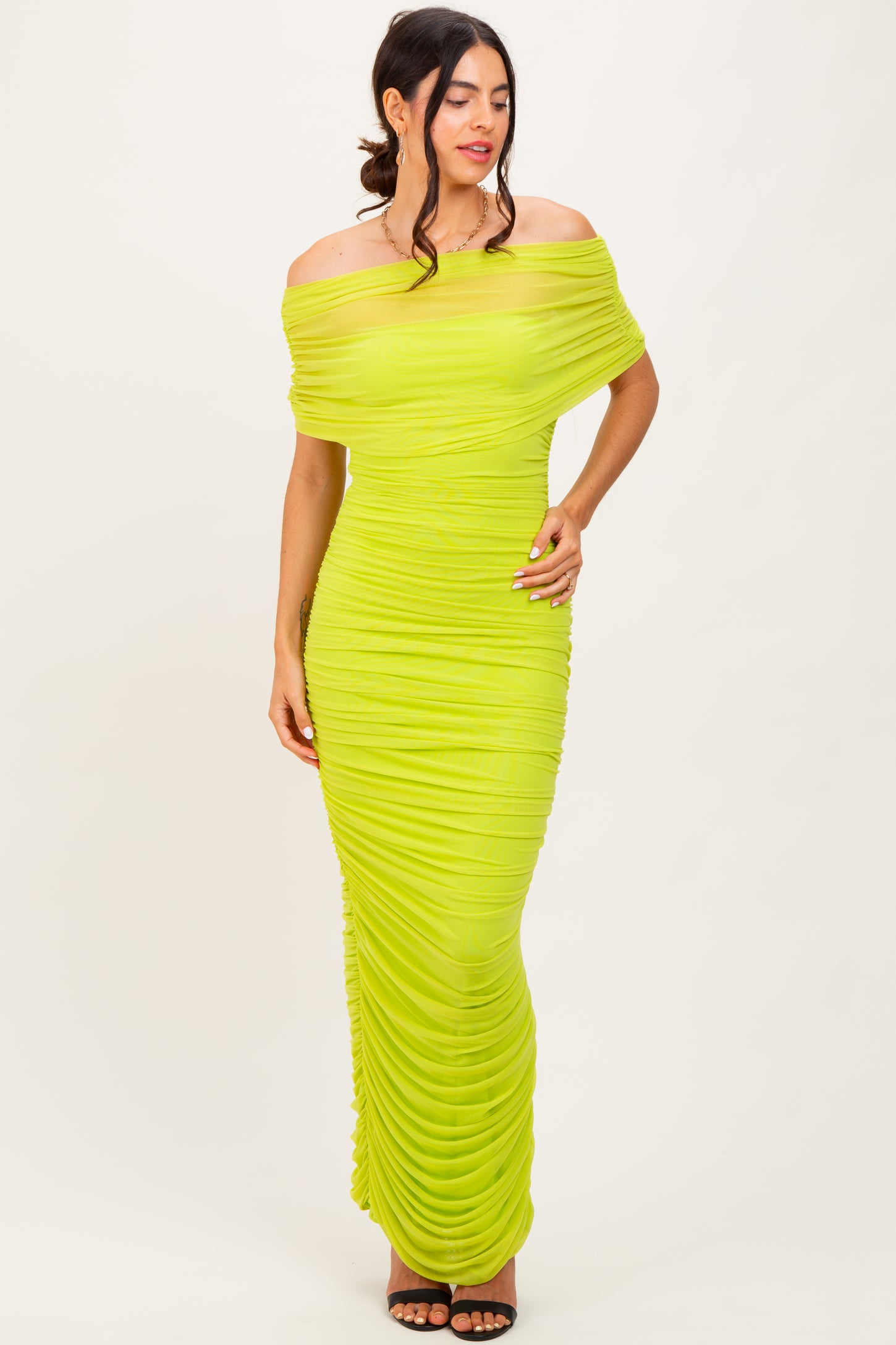woman wearing a bright lime green off-the-shoulder ruched maxi dress with a fitted silhouette