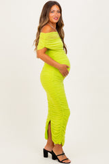 woman wearing a neon green off-the-shoulder maternity dress with gather detail and a visible baby bump