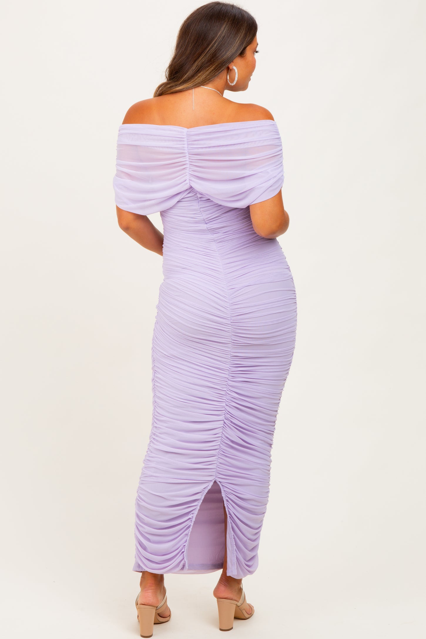 woman wearing a lavender off-shoulder maternity dress with ruched details and a back slit