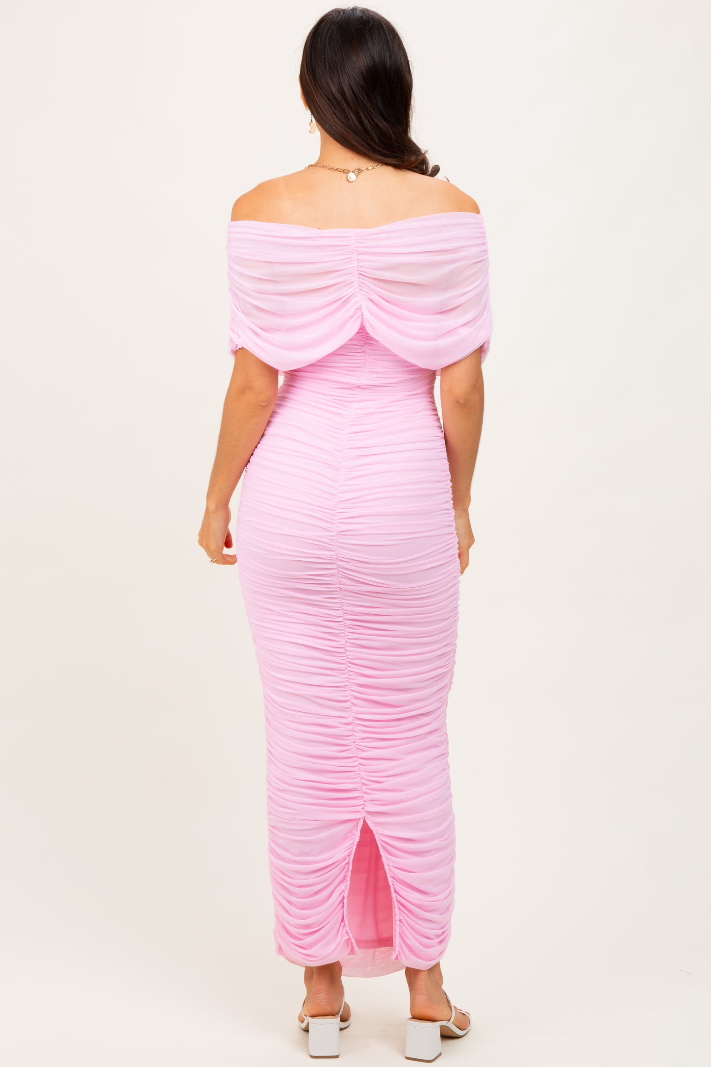 woman wearing a pink off-shoulder maxi dress with ruching details and a back slit