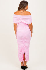 woman wearing a pink off-the-shoulder maternity dress with ruching and a back slit