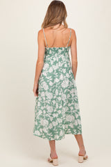 woman wearing a green floral maternity dress with smocked back and spaghetti straps, showing her baby bump