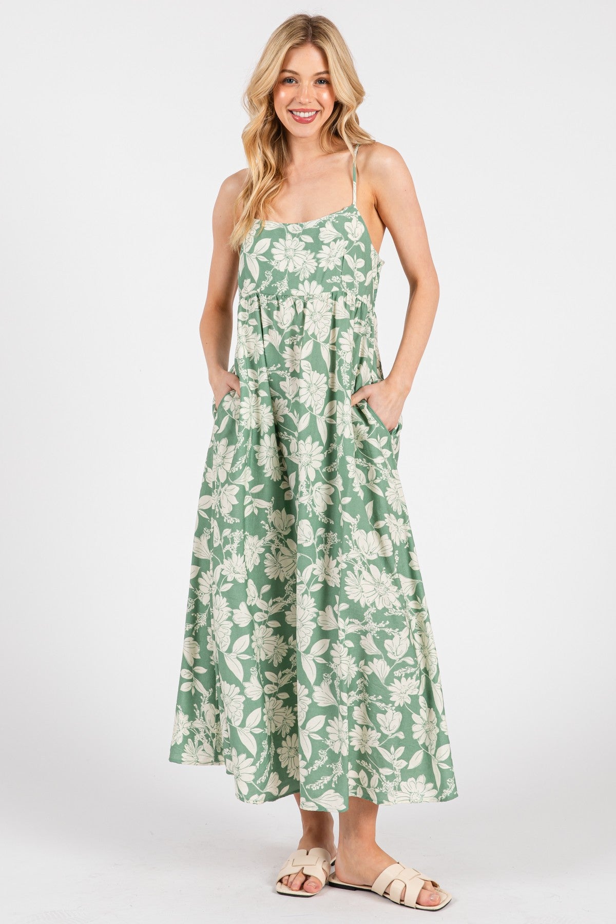woman wearing a green floral maxi dress with pockets and adjustable straps