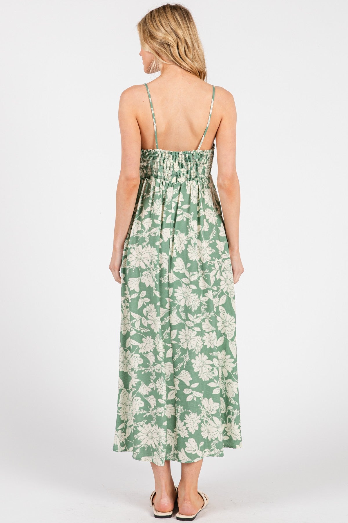 woman wearing a green floral maxi dress with a smocked back and thin straps, shown from the back