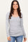 woman wearing a grey long sleeve scoop neck top paired with blue jeans and smiling