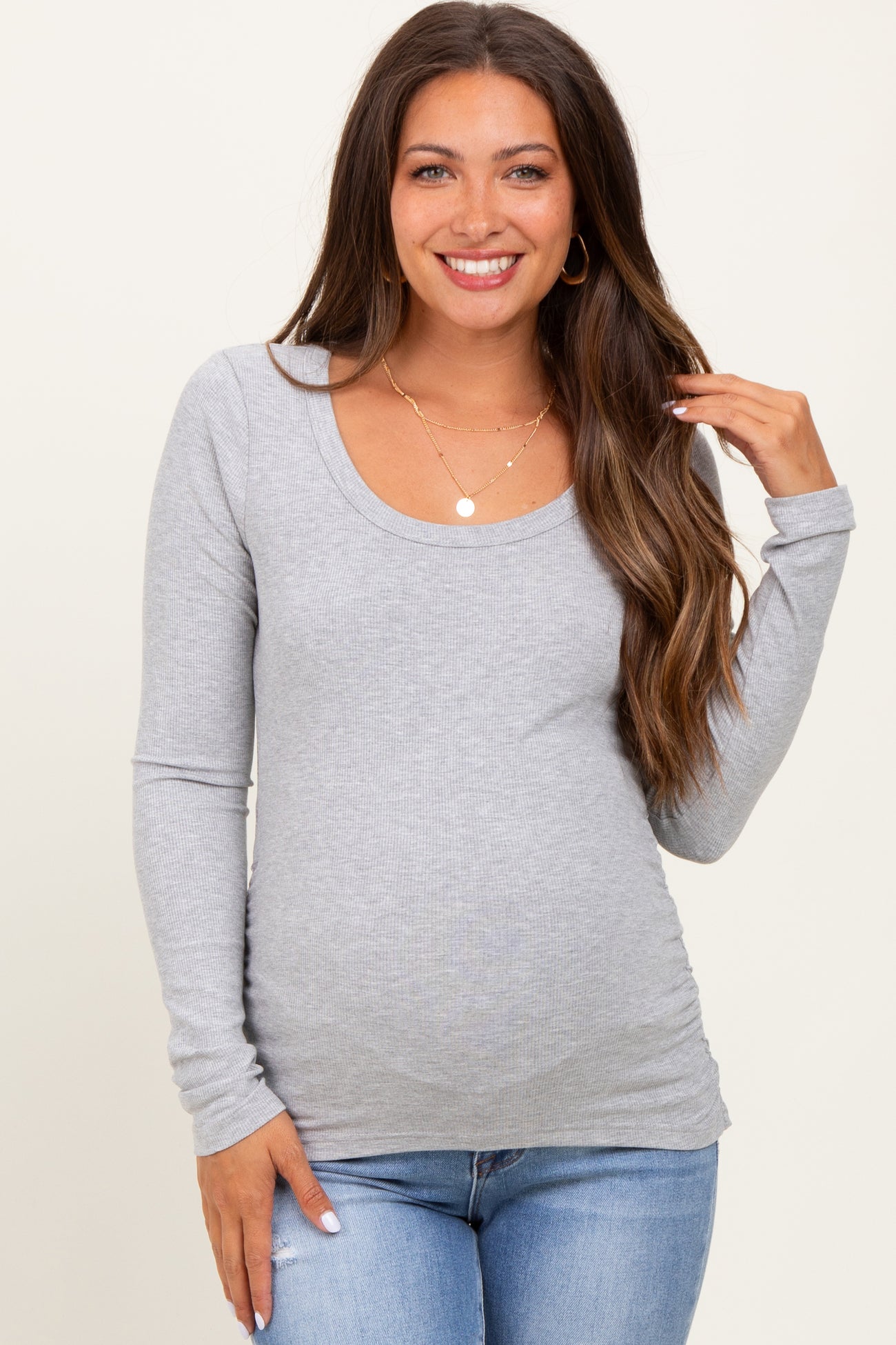 woman wearing a gray long sleeve maternity top with a scoop neckline and a visible baby bump