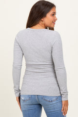 woman wearing a fitted gray long sleeve maternity top seen from the back, paired with blue jeans