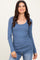 woman wearing a fitted blue long sleeve ribbed top with a scoop neckline and smiling