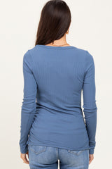 woman wearing a fitted blue ribbed long sleeve top, viewed from the back with casual denim jeans
