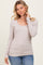 woman wearing a light taupe long sleeve scoop neck top with ribbed texture and fitted style paired with jeans