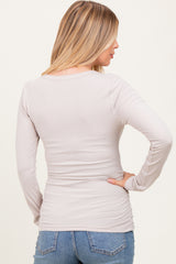 woman wearing a light gray long sleeve maternity top with a fitted style, showing the back view and no visible baby bump
