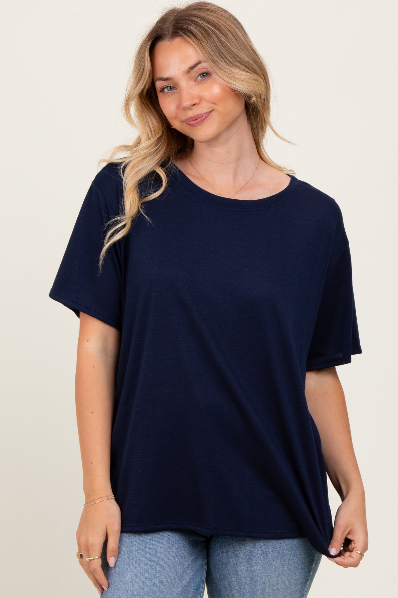 woman wearing a navy blue oversized t-shirt paired with light blue jeans, smiling at the camera.