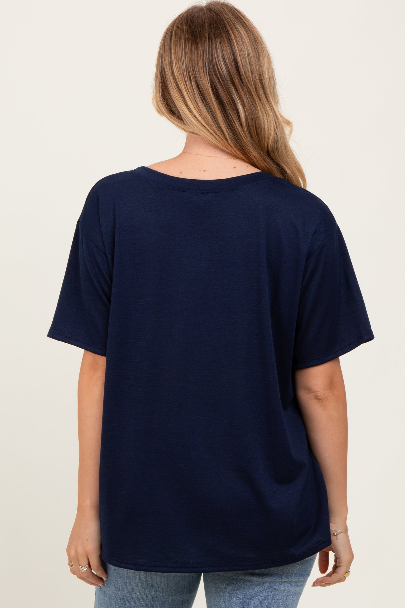 woman wearing a navy blue oversized t-shirt, viewed from the back, paired with light blue jeans