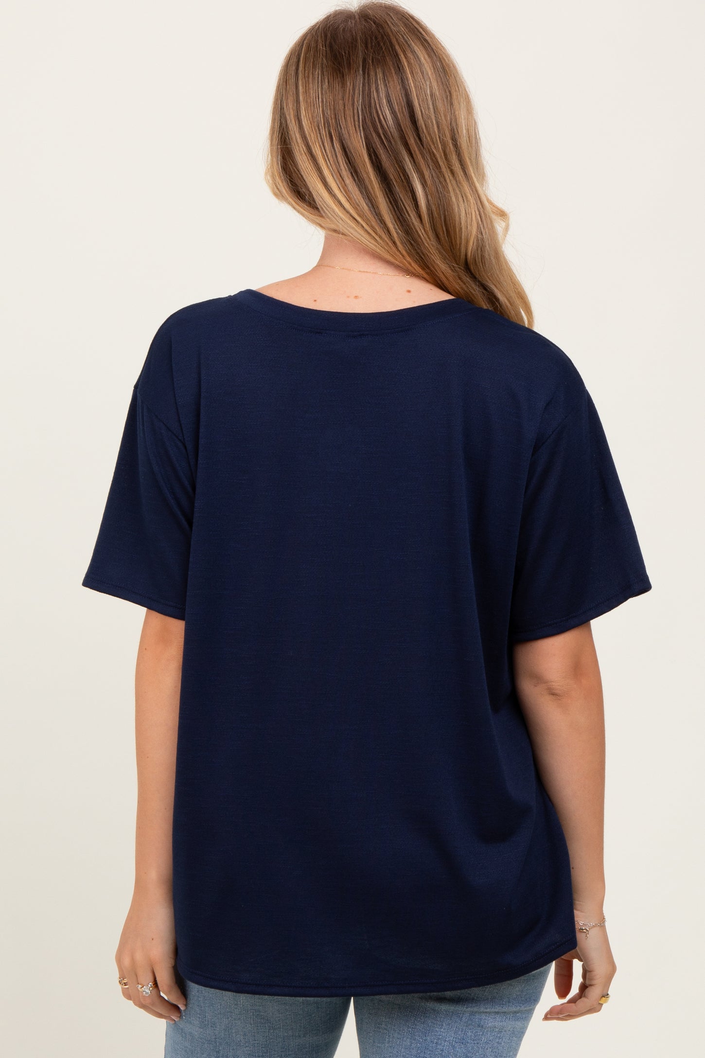 woman wearing a navy blue oversized t-shirt, viewed from the back, paired with light blue jeans