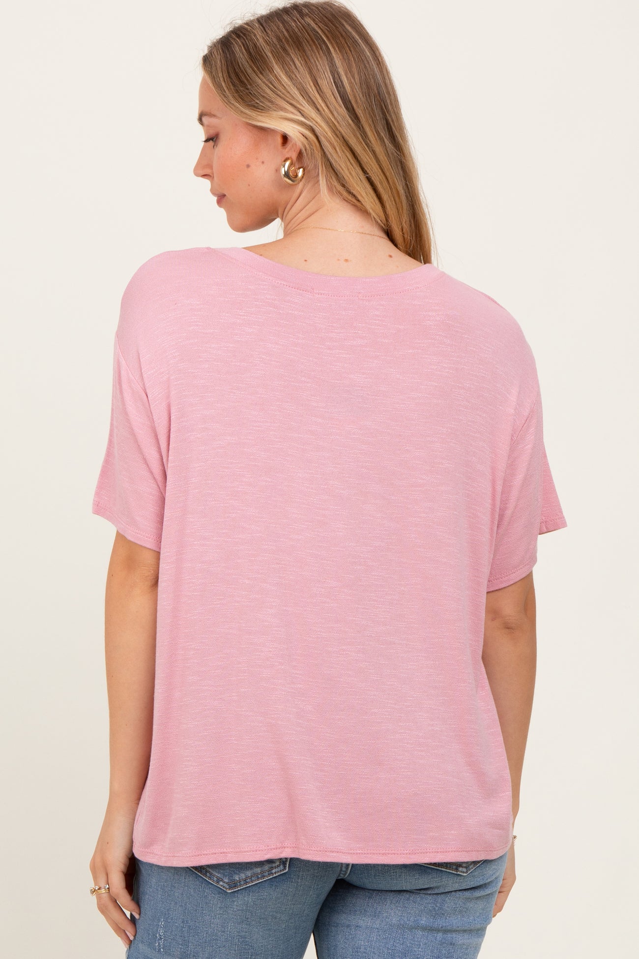 woman wearing a pink relaxed fit short sleeve top, showing the back view with casual style and soft fabric