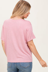 woman wearing a light pink maternity top with short sleeves, viewed from the back, paired with blue jeans