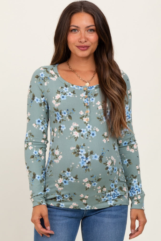 woman wearing a green floral maternity top with long sleeves and buttons, showcasing her baby bump