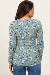 woman wearing a floral long sleeve maternity top in green with a fitted style, showing the back view