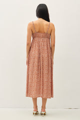 woman wearing a back view of a rust-colored maxi dress with a diamond pattern and adjustable straps