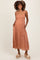 woman wearing a rust-colored maternity dress with a diamond pattern, spaghetti straps, and pockets