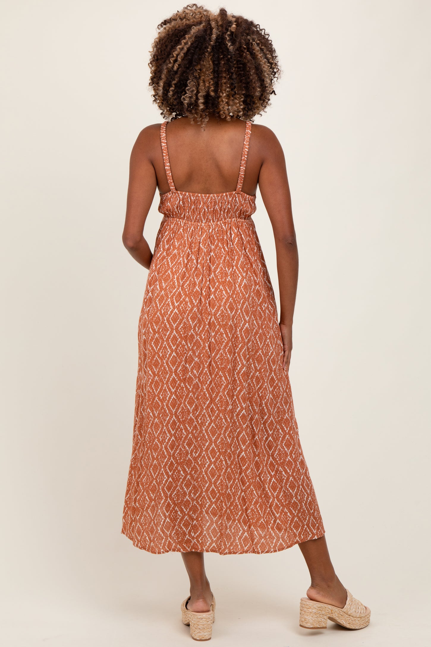 woman wearing an orange patterned maternity maxi dress with adjustable straps and a flowy silhouette