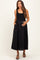 woman wearing a black maternity maxi dress with pockets and a fitted bodice, gently holding her baby bump