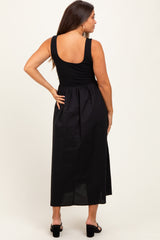 woman wearing a black maternity maxi dress with a fitted bodice and flowing skirt, featuring a back design detail