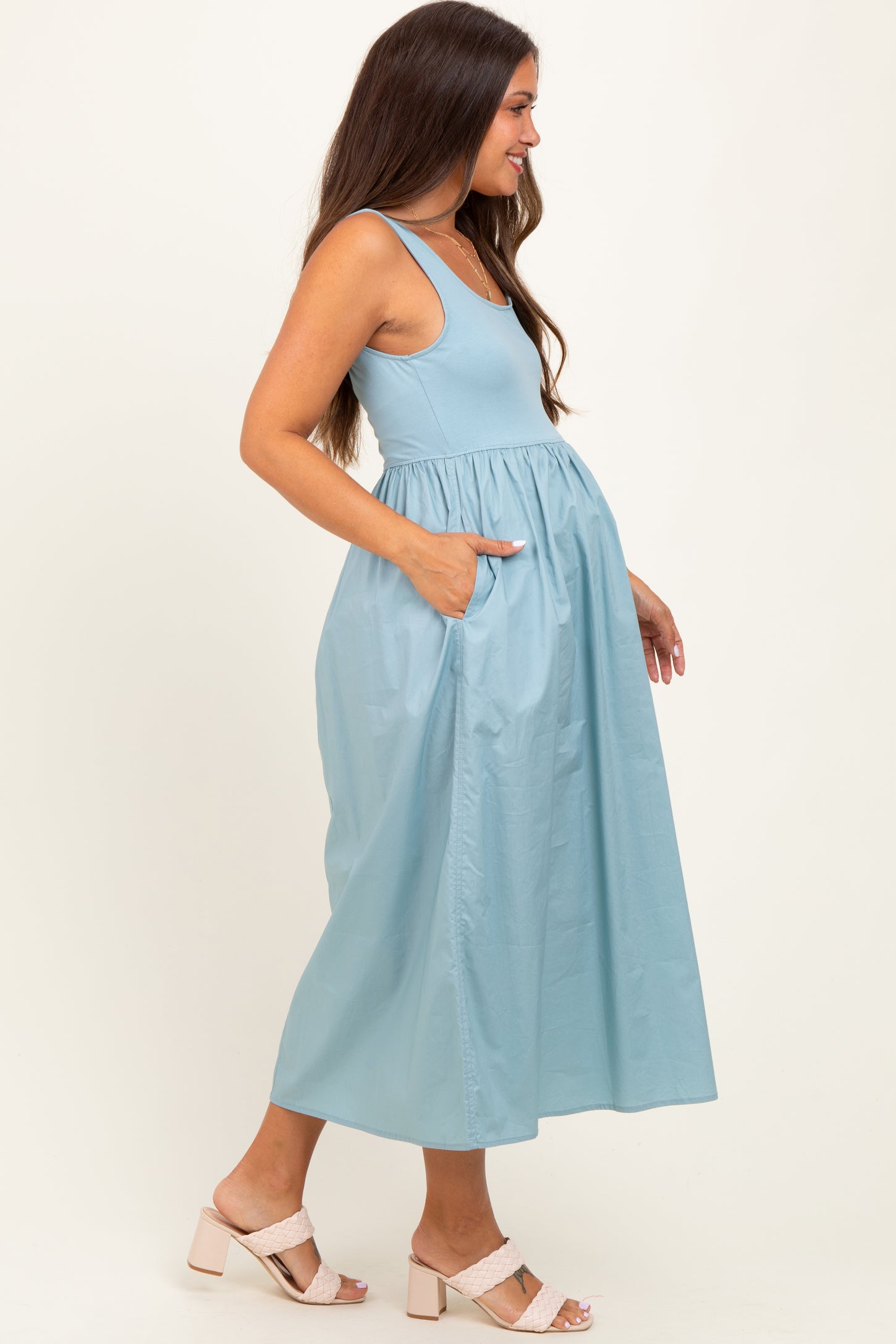 woman wearing a light blue maternity maxi dress with a fitted bodice and pockets, showcasing her baby bump