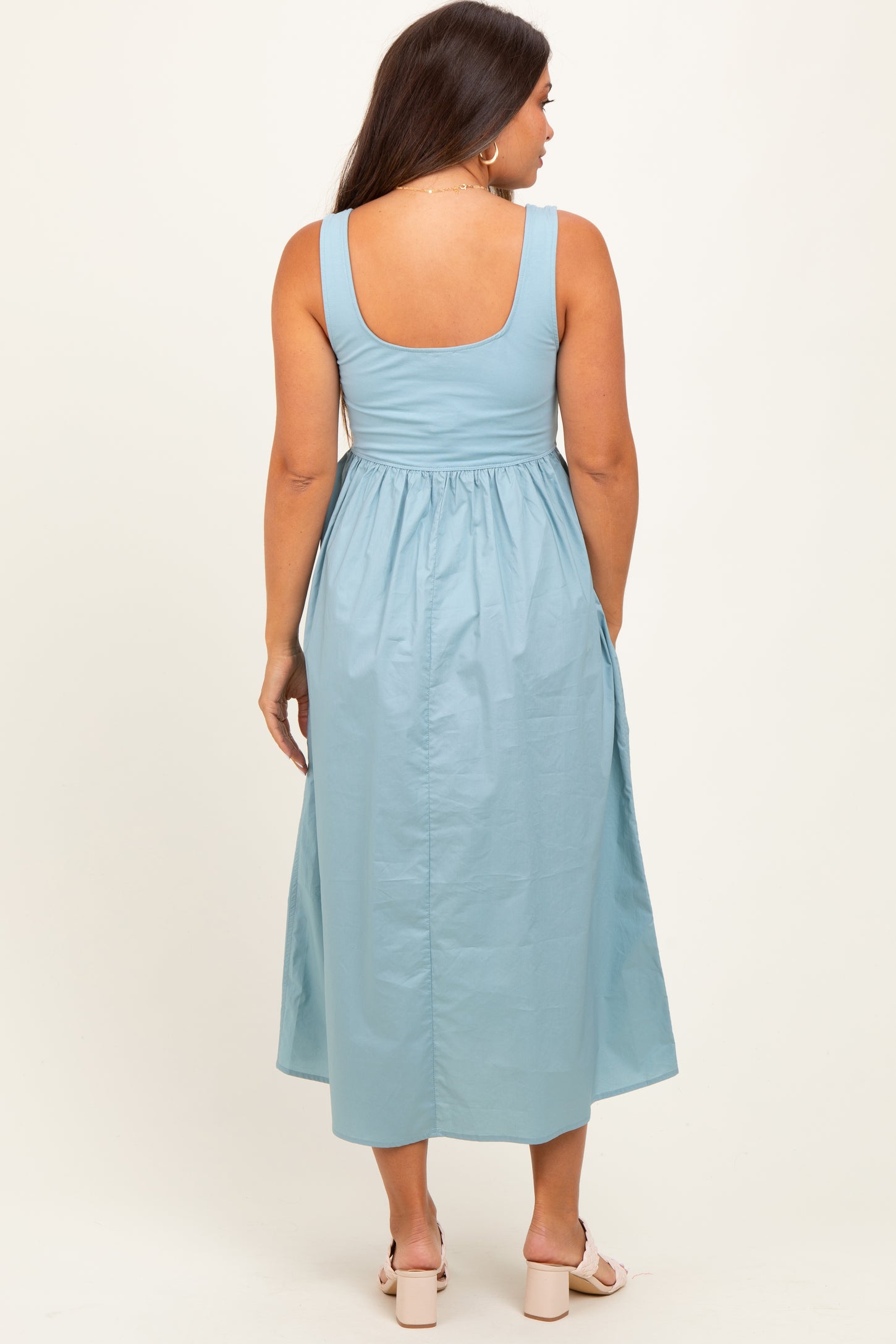 woman wearing a light blue maternity maxi dress with a fitted bodice and a flowy skirt, showing the back view