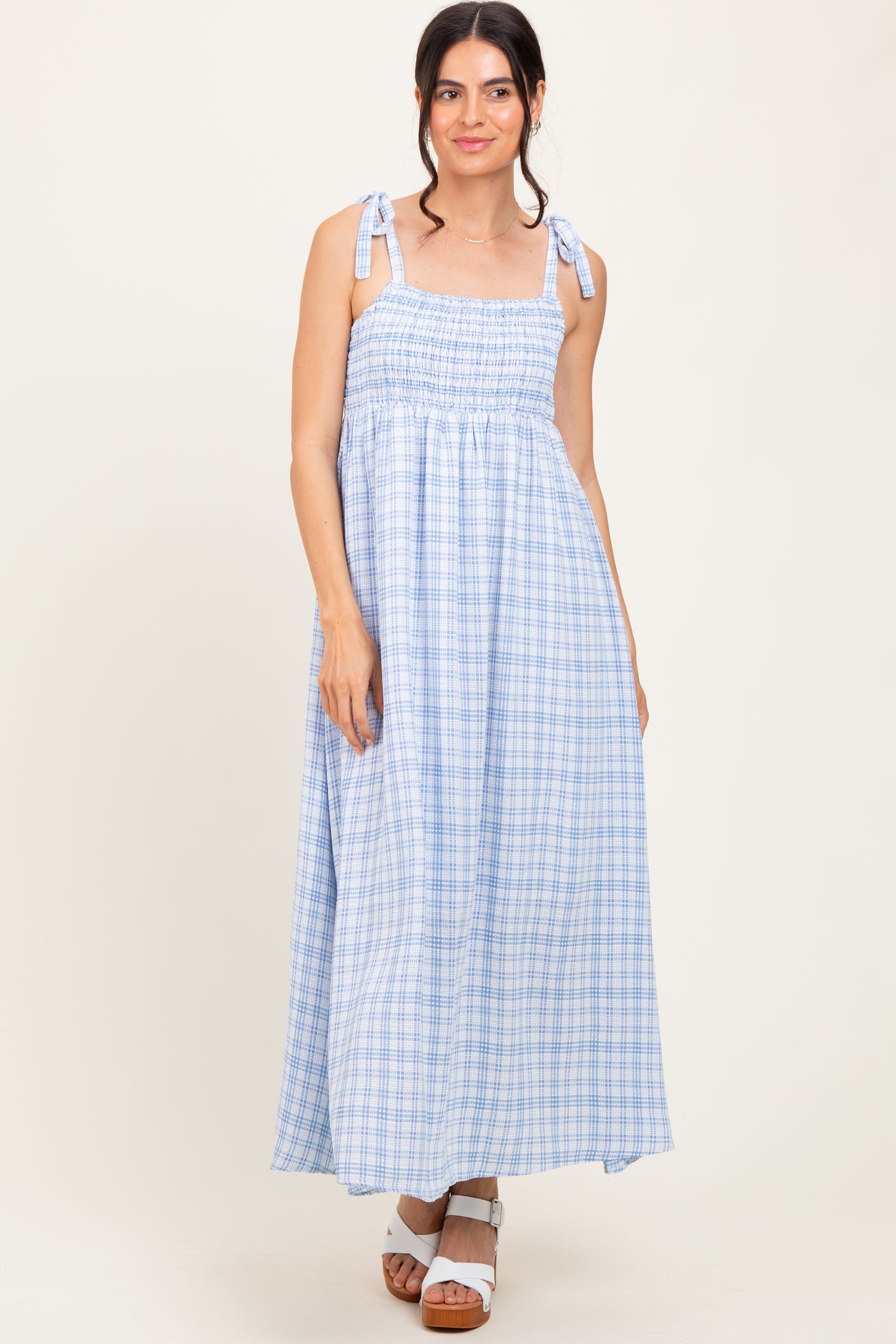 woman wearing a light blue plaid maxi dress with tie shoulder straps and a smocked bodice