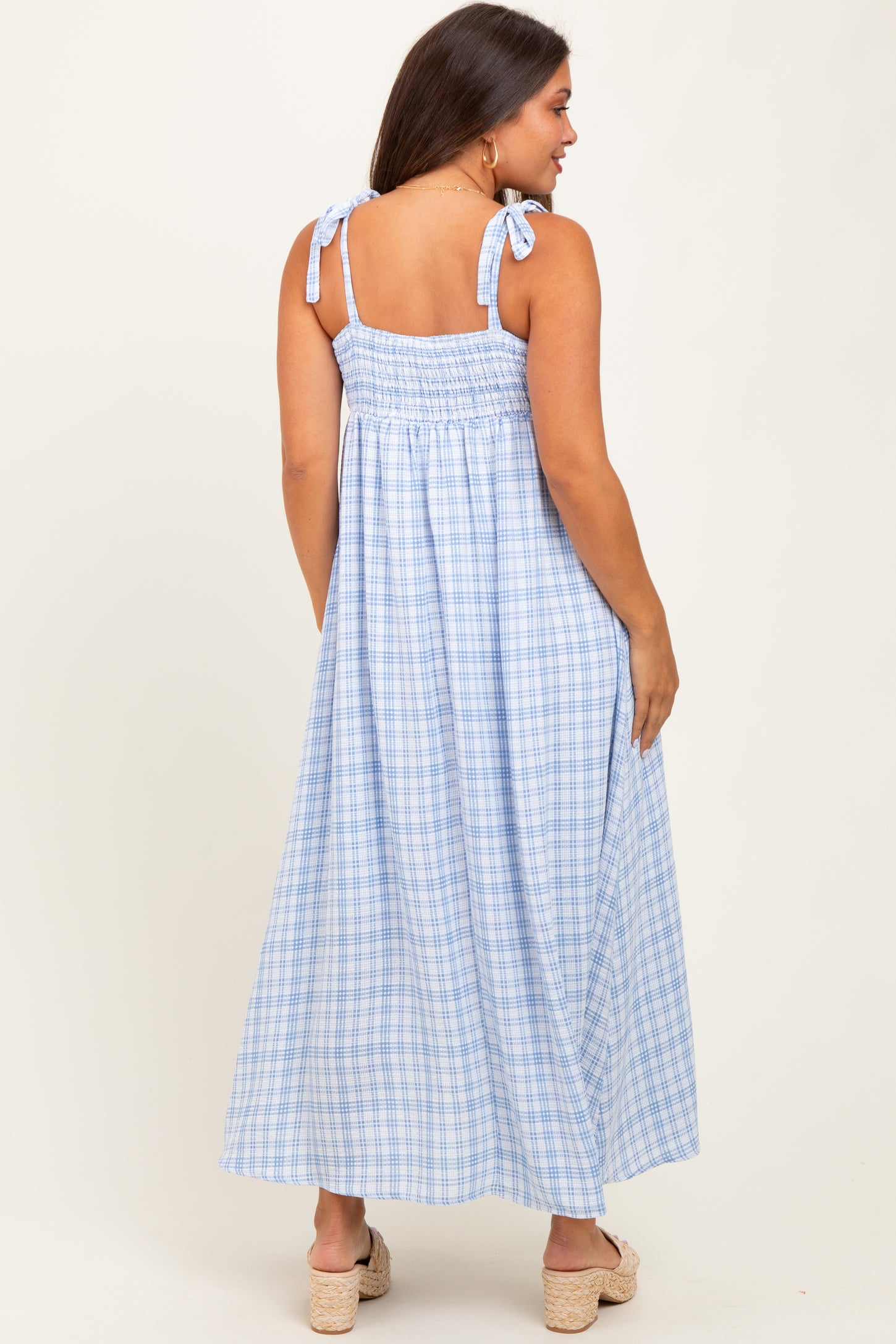 woman wearing a light blue plaid maternity maxi dress with tie shoulder straps and smocked back