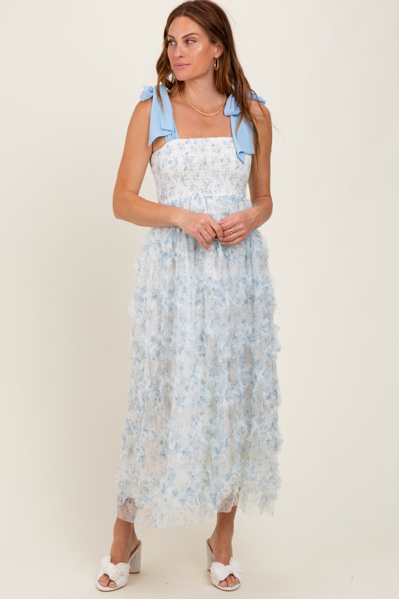 woman wearing a light blue floral maxi dress with smocked bodice and bow shoulder straps